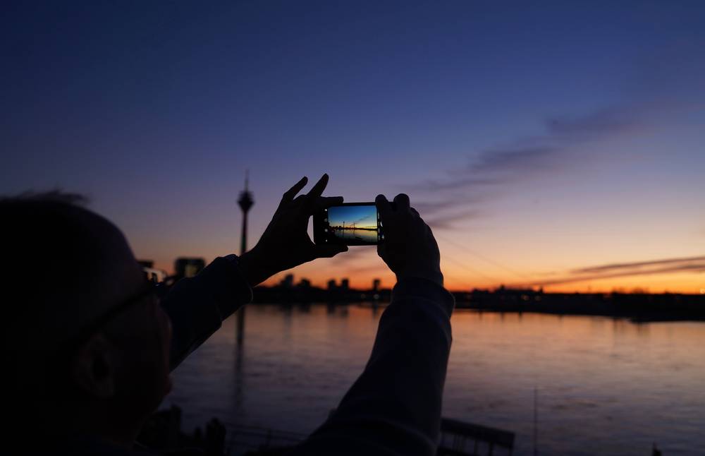 1 lovek-fotografiruet-ozero-na-fone-neba-vo-vrema-zahoda-solnca.jpg