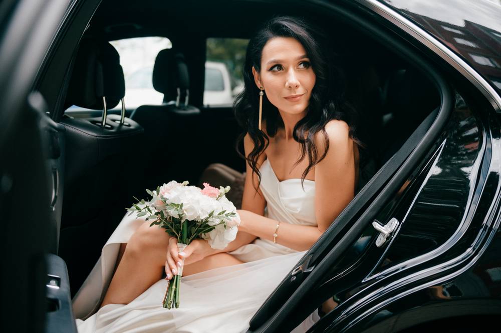 3 young-happy-bride-outdoor-portrait-smiling-bride-elegant-white-dress-holding-boquet-flowers-looking-out-car-wedding-day.jpg